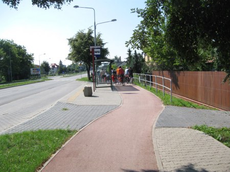 Droga rowerowa omija przystanek komunikacji miejskiej.