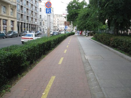 Wydzielona droga rowerowa z kostki bezpiecznie obniżona względem chodnika prefabrykowanym obrzeżem.