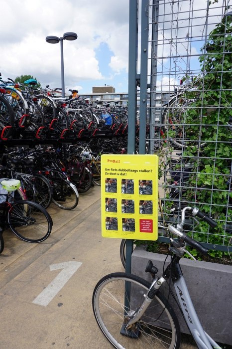 Parking rowerowy na dworcu w Goudzie. Żółta tablica to instrukcja korzystania z dwupoziomowych stojaków.